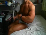 Sexy huge bodybuilder flexing on bed